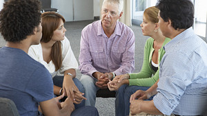 Group of people of mixed ages sitting together and talking in a circle