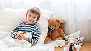 Child in bed with a thermometer in his mouth.