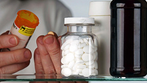 Person getting prescription pill bottle out of medicine cabinet